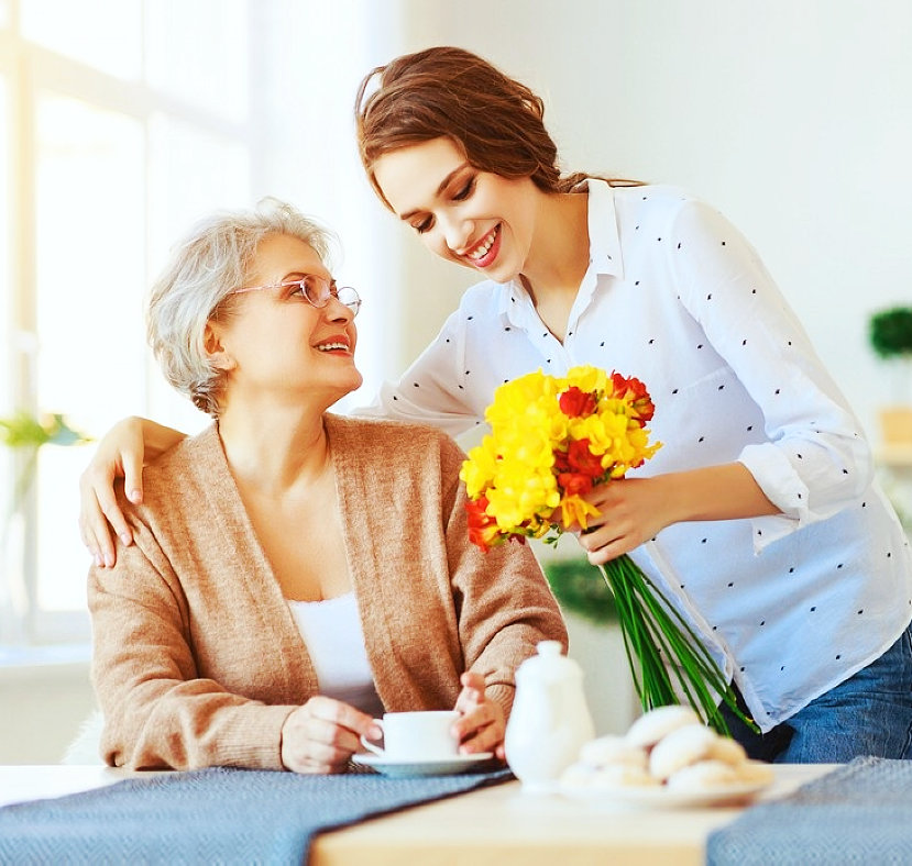 caregiver giving a flower to an elder woman
