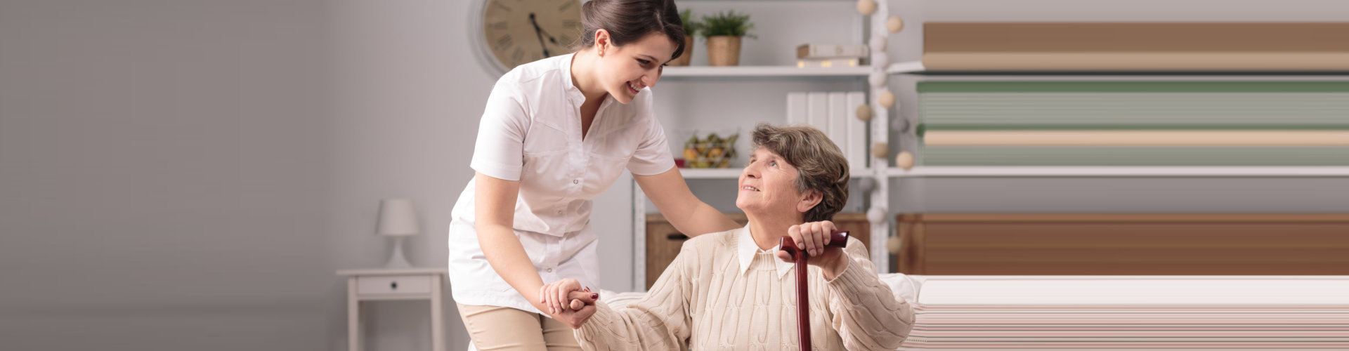 caregiver assisting elder woman on standing up using a walker